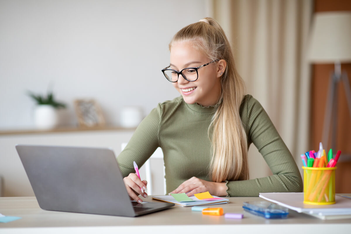 cute teen girl taking notes and using laptop XU2JZR4.jpg